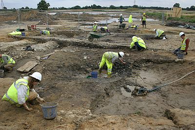 Prehistoric and Roman waterhole in the course of excavation (foreground) with associated complex of intercutting. linear landscape divisions beside it (left). &copy;YAT