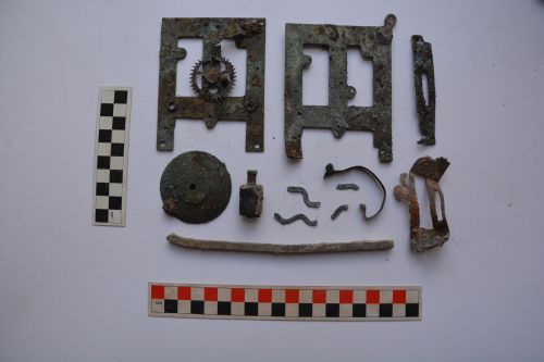 multiple fragments of a clock mechanism next to measuring equipment
