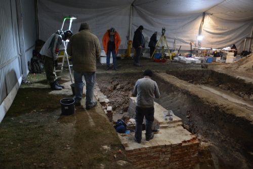 a group of people working on an archaeological trench inside a 