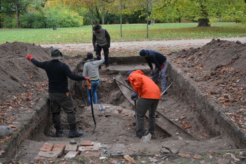 a group of people digging an archaelogical trench in a park