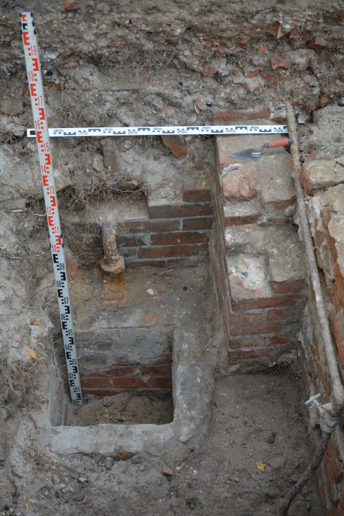 remains of a water installation in archaeological trench, and measuring equipment