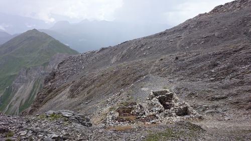 a ridge with a mountain range in the distance and a ruined structure in the foreground