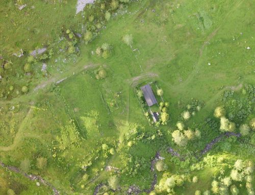 An aerial view of a building, fields and stream