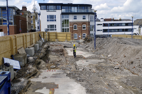 excaved trench surrounded by modern buildings