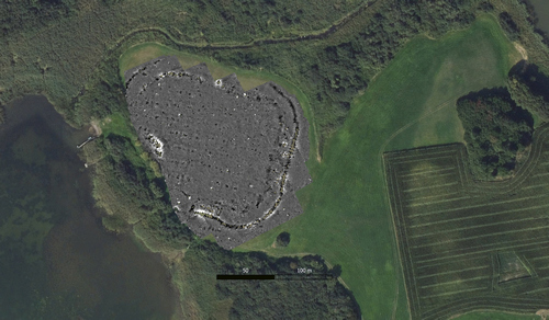 An aerial satellite view of a landscape bordering a body of water, partially overlaid by a magnetometry survey map